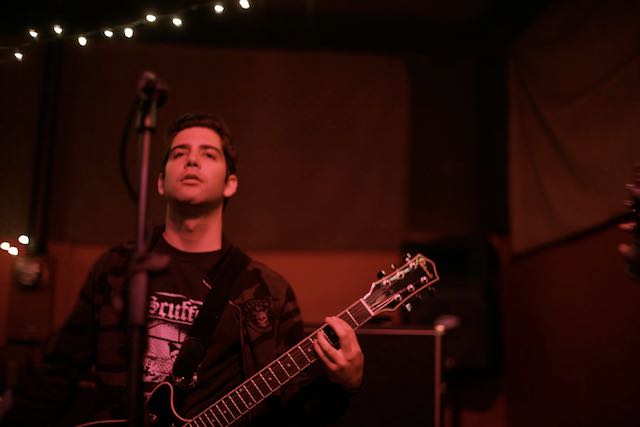 A photograph of Mark Sylvis holding his guitar